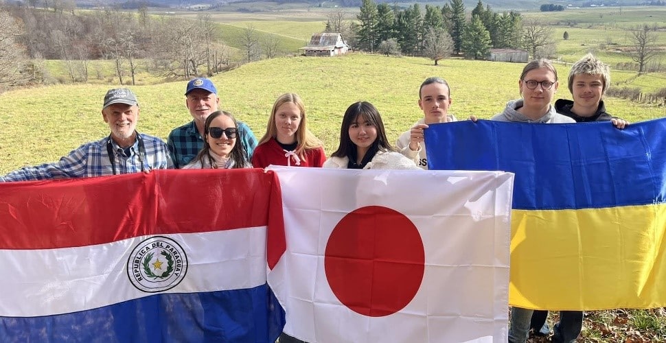 Rotary youth exchange students hold flags from France, Japan, and Ukraine.